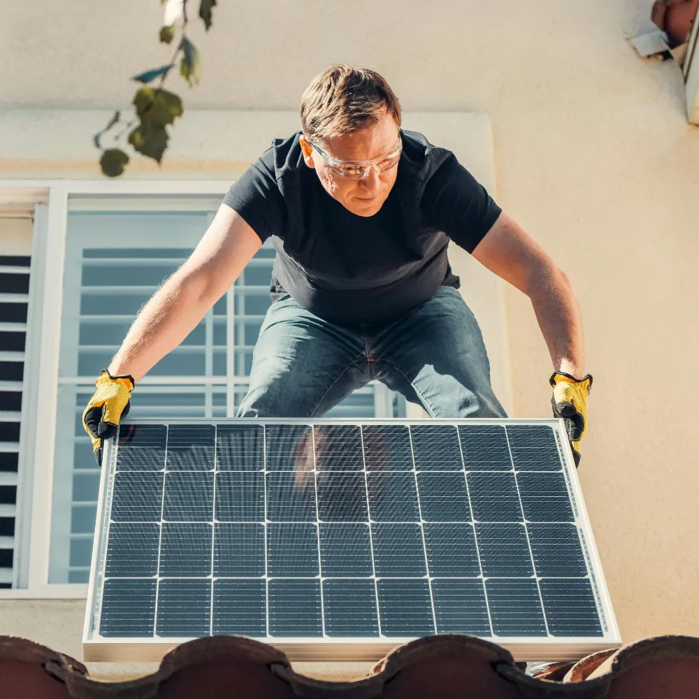 Čovek postavlja solarni panel na krov kuće.