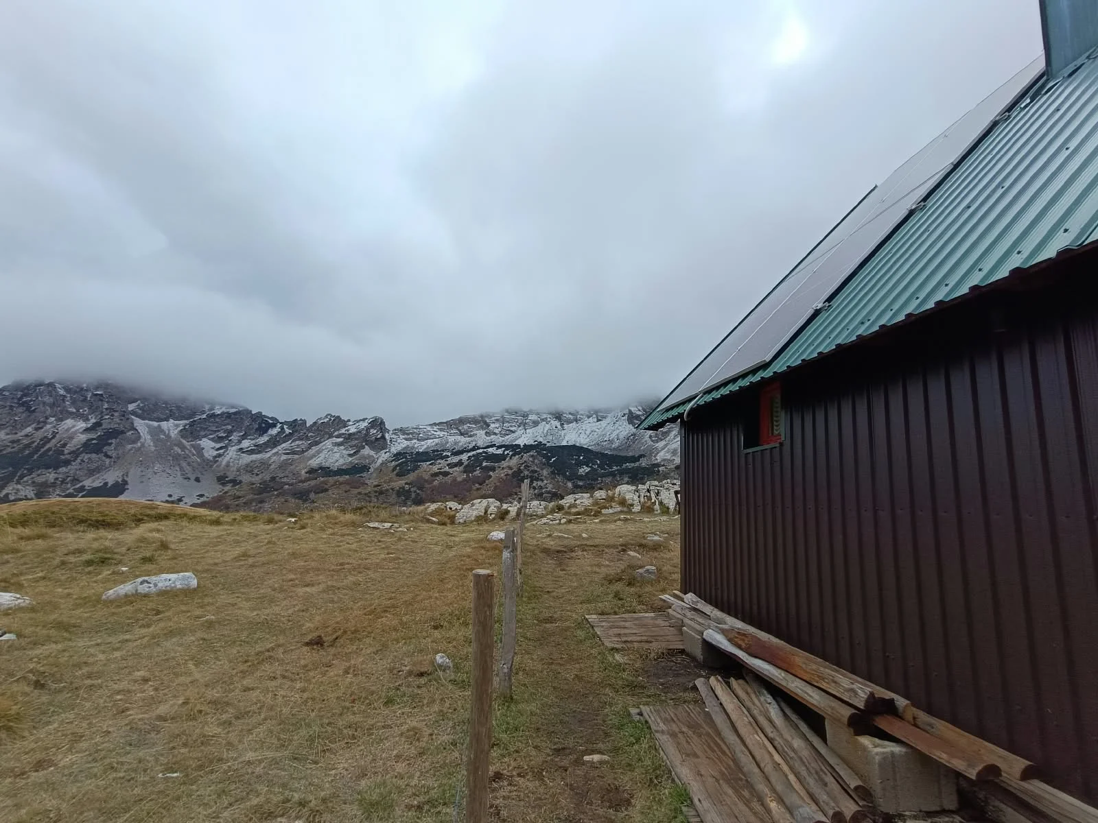 Solar panels on the konoba roof with snowy Durmitor peaks in the clouds behind