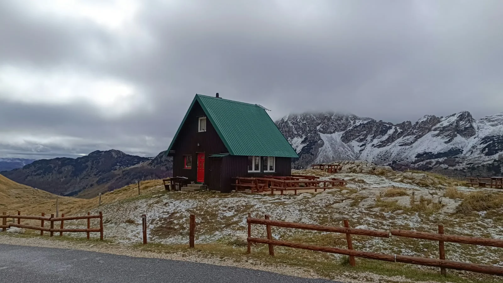 Konoba with a red door and summer terrace against the snowy Durmitor mountains